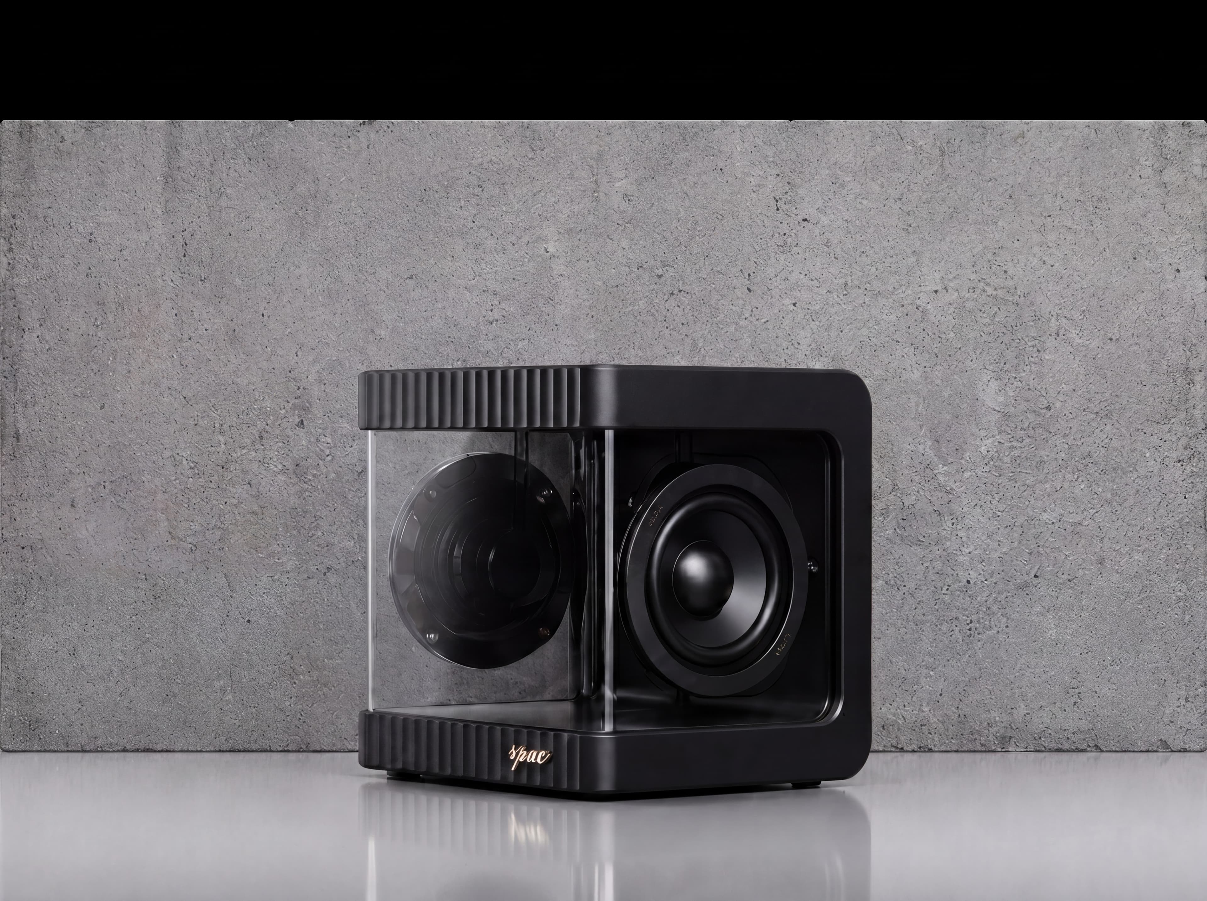 Compact desktop speaker on concrete surface — product hero